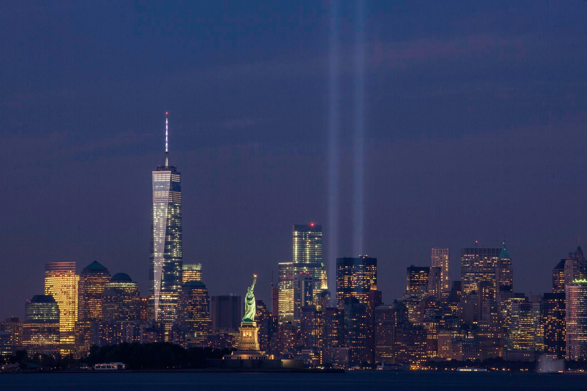 A photograph of the New York City skyline at night, including two beams of light commemorating the fallen towers of the World Trade Center.