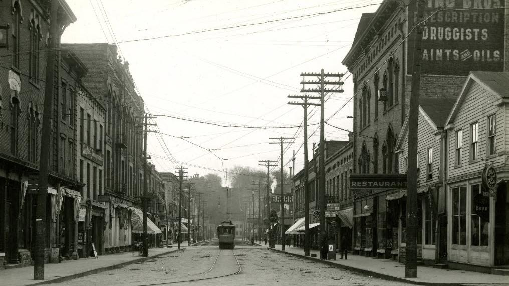 A streetcar runs down the middle of Main Street in Stillwater while buildings full of small businesses line each side of the road